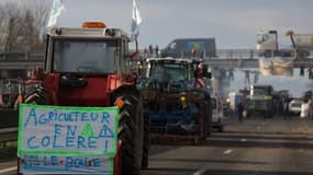 Cette photographie prise le 22 janvier 2024 montre un tracteur avec une banderole sur laquelle est écrit « agriculteur en colère » alors que les agriculteurs continuent de bloquer l'autoroute A64 pour protester contre la fiscalité et la baisse des revenus, près de Carbonne, au sud de Toulouse.