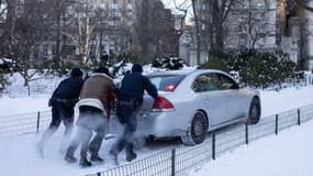 Des New Yorkais tentent de dégager une voiture bloquée par la neige. 