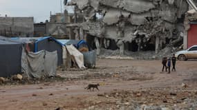 Des enfants dans les rues, près d'un camp de fortune et d'immeubles détruits, près d'un an après les séismes qui ont fait plus de 60.000 morts en Turquie et en Syrie, à Jandairis, en Syrie, le 3 février 2024