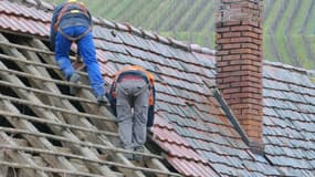 Des ouvriers remplaçants les tuiles d'un toit