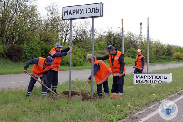 Des employés municipaux changent les panneaux routiers ukrainiens en russes à l'extérieur de la ville de Marioupol le 5 mai 2022