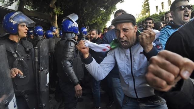 Les forces de sécurité algériennes entourent des manifestants qui organisent une manifestation anti-gouvernementale à Alger le jour de l'élection présidentielle. RYAD KRAMDI / AFP