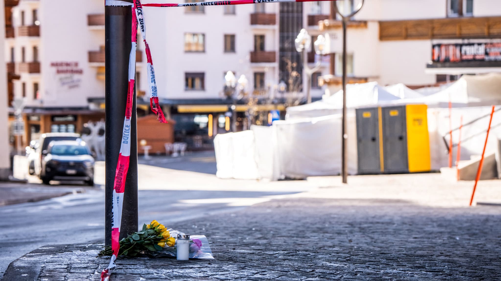 Des fleurs et des bougies déposées sur le sol près du bar Le Constellation après l'incendie qui a ravagé l'établissement à Crans-Montana, pendant les célébrations du Nouvel An, le 1er janvier 2026