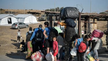 Des migrants attendent pour être dirigés vers un nouveau campement de réfugiés après l'incendie du camp de Moria, sur l'ile de Lesbos, le 12 septembre 2020