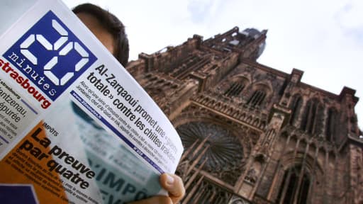 Une personne lit le quotidien gratuit "20 Minutes", le 15 septembre 2005 devant la cathédrale de Strasbourg, au lendemain du lancement de la huitième édition.