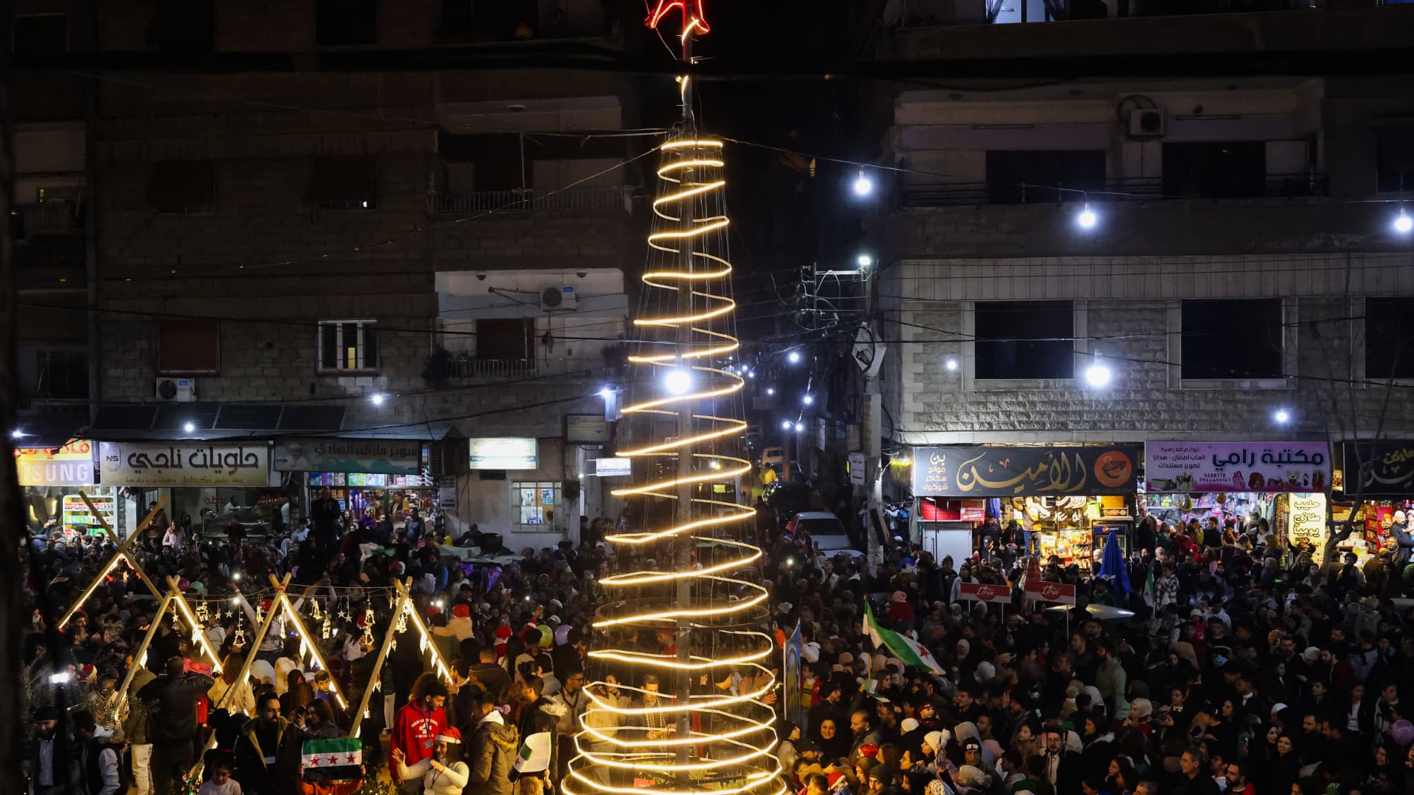 Des personnes célèbrent l'illumination de l'arbre de Noël dans la région de Jaramana, près de Damas, en Syrie, le 22 décembre 2024.