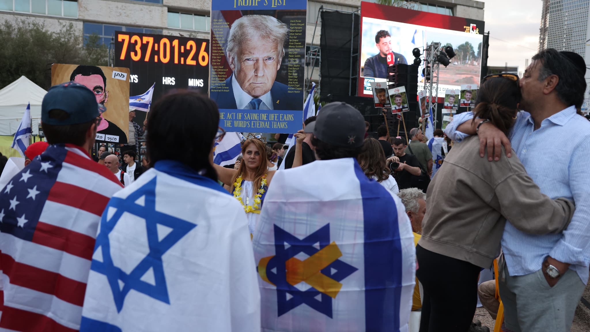 People draped in American and Israeli flags wait for the release of Israeli hostages from Gaza in Hostage Square in Tel Aviv, early in the morning on October 13, 2025.