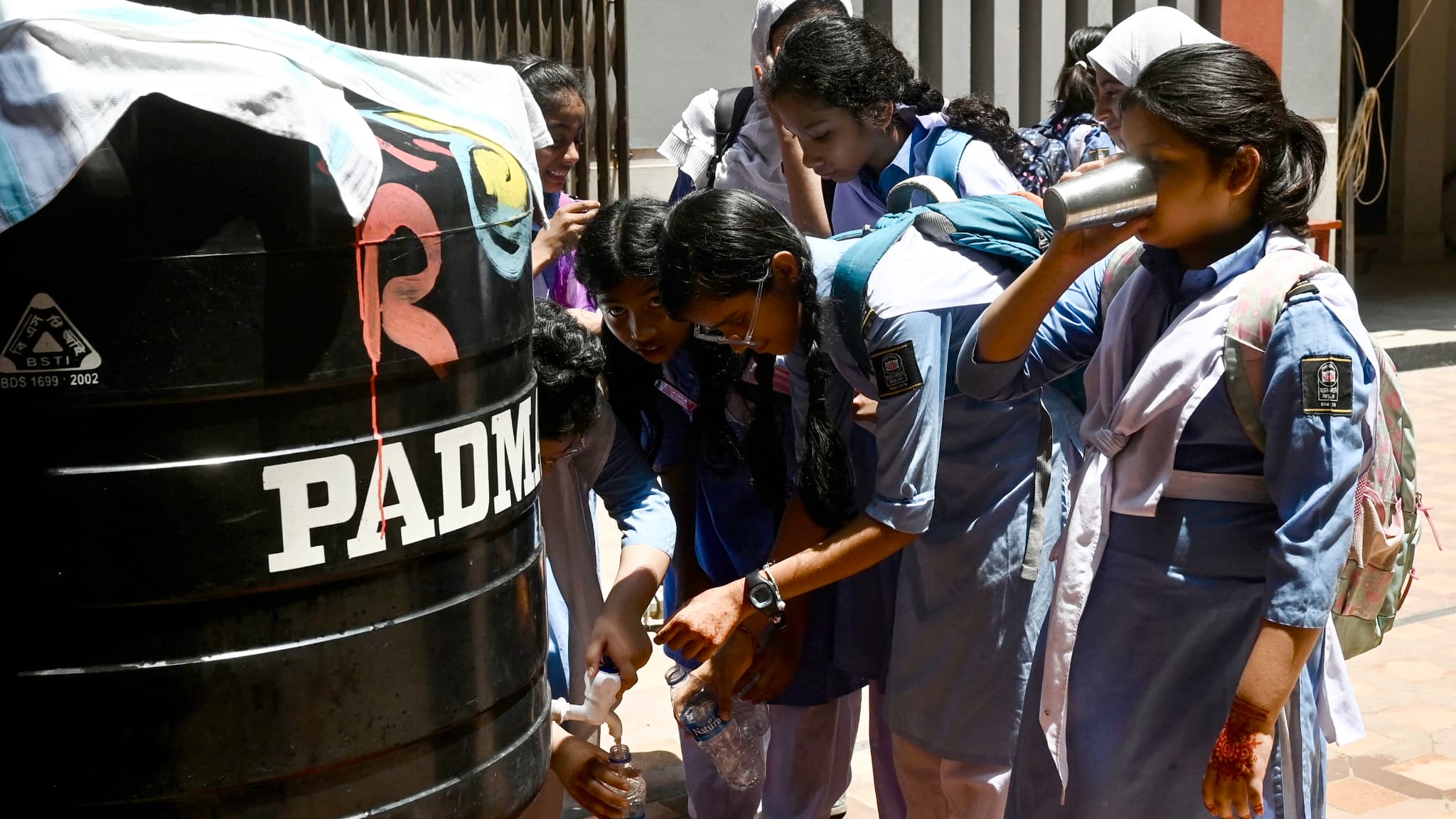 Des élèves remplissent leurs bouteilles pour s'hydrater lors d'une chaude journée d'été, dans une école de Dhaka, le 28 avril 2024, en raison de la vague de chaleur actuelle. 