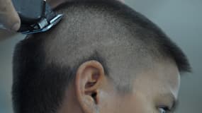 Un coiffeur rasant la tête d'un écolier dans un salon de coiffure près d'une école à Bangkok, en Thaïlande, le 31 juillet 2013. (illustration)