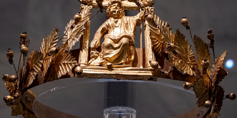 Cette photo, prise le 10 mai 2023, montre une couronne d'or ornée de feuilles et de branches de vigne, entourant une représentation du dieu Sérapis, entouré de bustes miniatures des divinités Isis et Harpocrate, sur la façade d'un temple datant du IIe siècle. Cette couronne fait partie du trésor de Douche (Dush), découvert en 1989 dans l'oasis de Kharga, caché dans le mur d'un fort romain. Elle est aujourd'hui exposée au Musée national de la civilisation égyptienne, dans le quartier de Fustat, au Caire.
