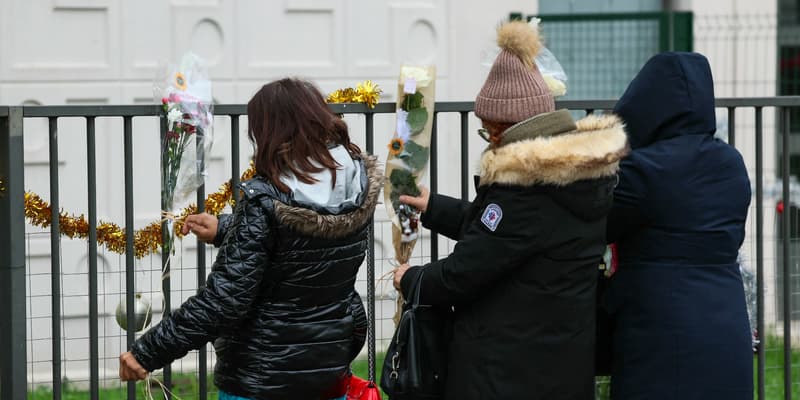 Des personnes déposent des fleurs devant l'appartement du rez-de-chaussée où les corps d'une femme et de ses quatre enfants ont été découverts, à Meaux, dans l'est de Paris, le 26 décembre 2023.