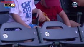 Un petit garçon se bat avec son hot dog lors d’un match de baseball