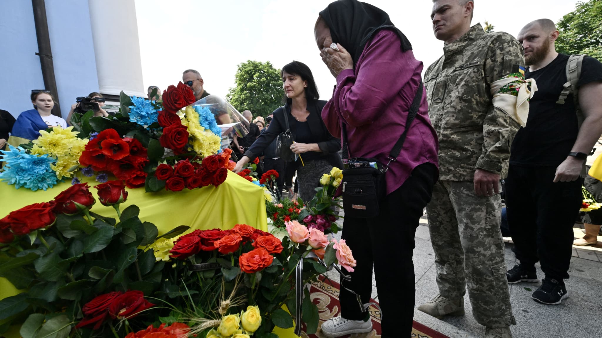 Des personnes en deuil rendent hommage à Roman Ratuchny lors de sa cérémonie funéraire dans une cour de la cathédrale Mykhaylo Golden Doms à Kiev le 18 juin 2022. 
