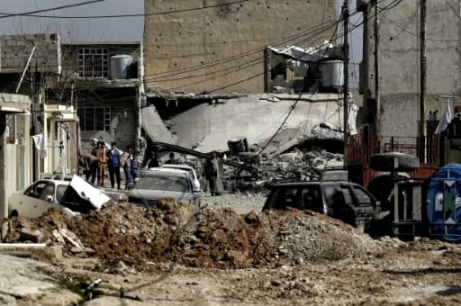 Des habitants au milieu d'un quartier en ruines le 1er mars 2017 à Mossoul Des habitants au milieu d'un quartier en ruines le 1er mars 2017 à Mossoul
