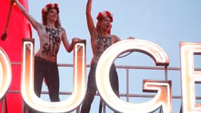 Deux Femen ont bravé la pluie pour dénoncer "'l'industrie du sexe", lundi 6 octobre, sur le toit du Moulin Rouge. Un action qui coïncidait avec les 125 ans du temple parisien du French Cancan.
