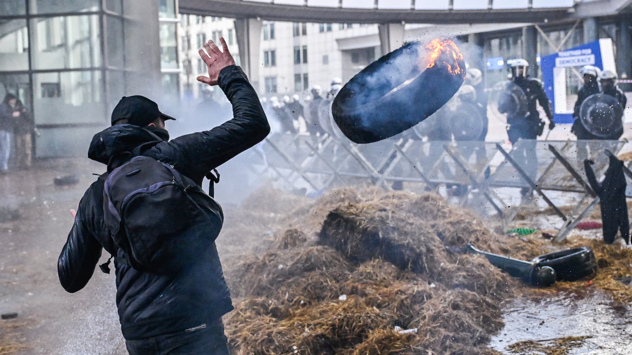 Un manifestant jette un pneu en flammes sur une botte de paille devant le Parlement européen à Bruxelles, dans le cadre de la manifestation des agriculteurs, le 1er février 2024