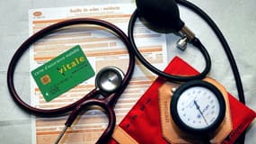 Une feuille de soins, une Carte d'assurance maladie Vitale, un stéthoscope et un tensiomètre, dans un cabinet médical (image d'illustration)
