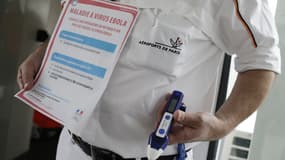 Un employé des urgences médicales des aéroports de Paris tient une note d'information sur le virus Ebola ainsi qu'un thermomètre