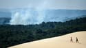 Deux personnes sur la la dune du Pilat d'où l'on voit la fumée s'élever de l'incendie qui s'est déclaré à La Teste-de-Buch (Gironde), le 16 juillet 2022 