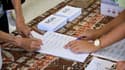Une personne signe la liste d'émargement dans un bureau de vote lors du 3e référendum d'autodétermination, le 12 décembre 2021 à Nouméa, en Nouvelle-Calédonie