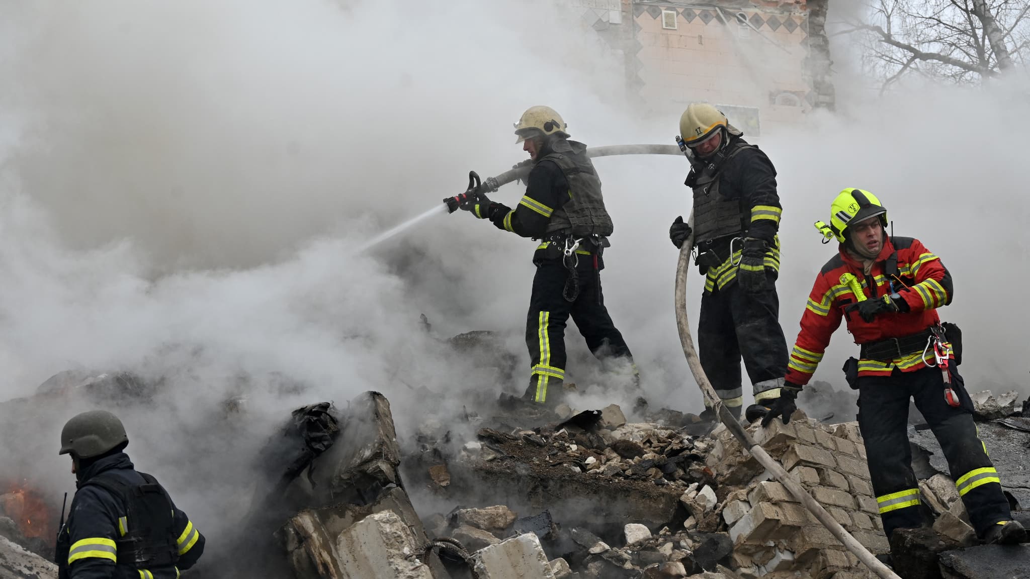 Des secouristes et des pompiers ukrainiens dégagent les débris sur le site d'une attaque au missile à Kharkiv, le 23 janvier 2024. 