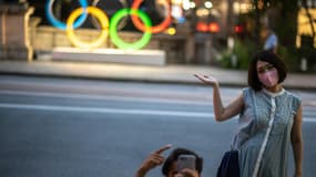 Un couple prend la pose devant les anneaux olympiques à Tokyo, le 10 juillet 2021