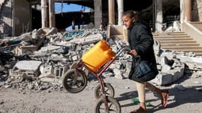 Une jeune fille pousse un chariot chargé d'un jerrycan devant les décombres d'un bâtiment détruit lors d'un bombardement israélien à Rafah, dans le sud de la bande de Gaza, le 14 février 2024.