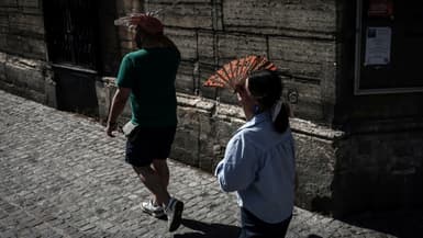 Des passants se protègent du soleil, le 1er juillet 2025 à Paris en période de canicule