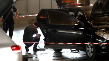 Un officier de la police scientifique examine une voiture abandonnée par Redoine Faïd et ses complices au centre commercial O'Parinor à AUlnay-sous-Bois, le 1er juillet 2018.