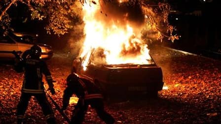 Pompiers tentant de contrôler l'incendie d'une voiture à Clichy-sous-Bois, fin octobre 2005. Le parquet de Bobigny (Seine-Saint-Denis) a requis un non-lieu pour deux policiers poursuivis pour la mort accidentelle par électrocution de deux adolescents, aff