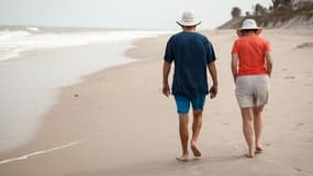 Deux personnes âgées se promenant sur une plage.