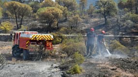 Des pompiers continuent d'arroser le site d'un incendie pour éviter des reprises de feu le 20 août 2021 aux Mayons, dans le Var