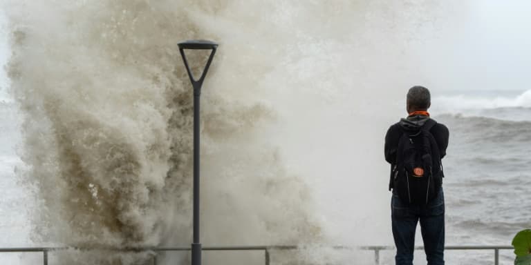 Un homme regarde les vagues sur à marée haute après le passage de l'ouragan Beryl à Saint-Domingue, le 2 juillet 2024