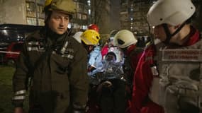 Une femme évacuée par les secours après une attaque de drones russes à Kiev le 23 mars 2025