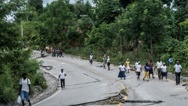 Des Haïtiens marchent le long d'une route endommagée par le séisme, le 16 août 2021 près de Camp Perrin, en Haïti