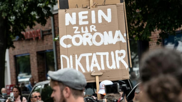 Des manifestants anti-confinement défilent à Berlin le 1er août 2021, portant une pancarte "Non à la dictature du Corona" Des manifestants anti-confinement défilent à Berlin le 1er août 2021, portant une pancarte "Non à la dictature du Corona"