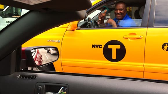 Un chauffeur de taxi admire la Mustang du haut de son SUV Toyota hybride.