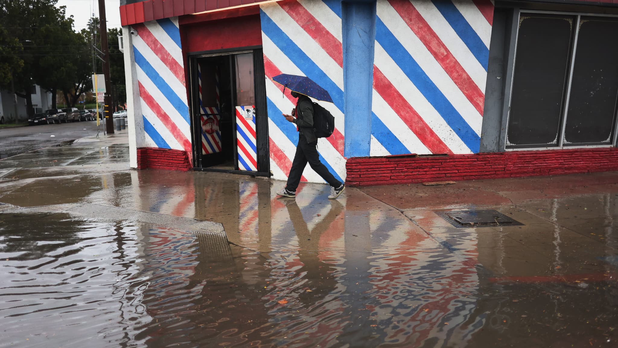 Un homme marche près d'une route inondée lors d'une tempête de pluie à Long Beach, en Californie, le 1er février 2024. 