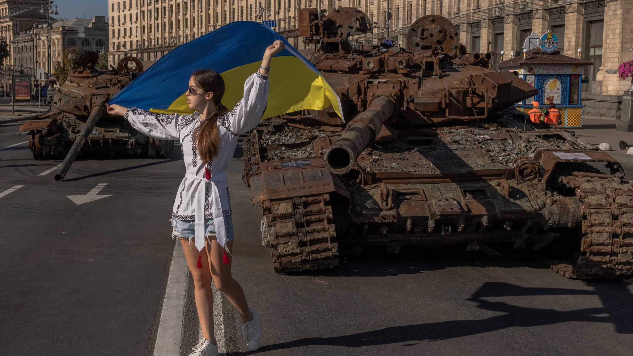 Une jeune femme pose avec un drapeau ukrainien devant des carcasses de chars russes, pour le Jour de l'Indépendance de l'Ukraine, à Kiev, le 24 août 2023