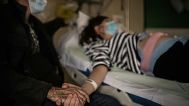 Un homme portant un masque de protection tient la main de sa femme enceinte à la maternité des Diaconesses à Paris, le 17 novembre 2020