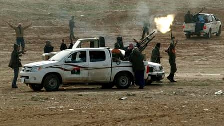 Des insurgés tirent sur des avions de chasse libyens non loin de Bin Djaouad, ville dont ils ont pris le contrôle en avançant sur la route de Syrte, le fief de Mouammar Kadhafi et leur prochain objectif. /Photo prise le 5 mars 2011/REUTERS/Goran Tomasevic