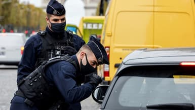Des policiers français contrôlent une voiture sur les Champs-Elysées à Paris, le 30 octobre 2020, premier jour du nouveau confinement contre le coronavirus