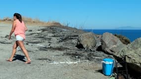 Une touriste marche à l'endroit où ont été brûlées des voitures à Sisco en Corse le 14 août 2016