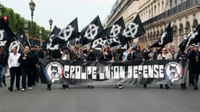 Des membres du groupe politique étudiant français GUD (Groupe Union Défense) brandissent une banderole et des drapeaux avec le symbole de la croix nationaliste celtique lors d'un rassemblement de groupes d'extrême droite français pour dénoncer la « mondialisation », à Paris, le 8 mai 2011.