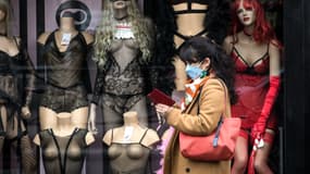 Une passante portant un masque devant un sexshop fermé dans le quartier de Pigalle, à Paris, le 16 mars 2020