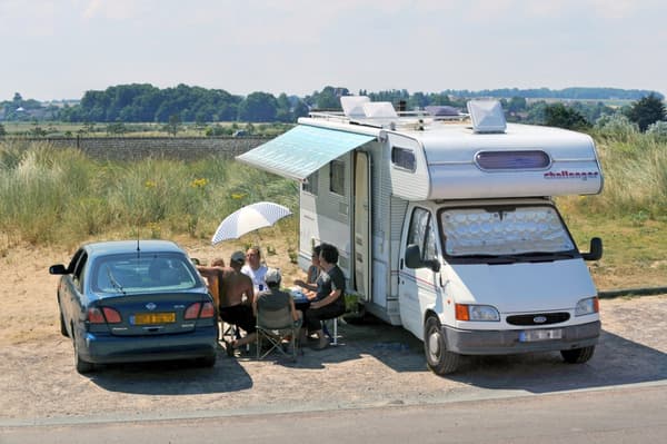 Des touristes en train de déjeuner devant leur camping-car près de La Graye-sur-Mer en Normandie.