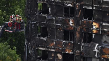 Des pompiers tentent d'accéder aux étages de l'immeuble dévasté par les flammes.