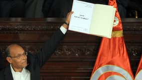 Le président tunisien Moncef Marzouki brandit une copie de la nouvelle Constitution, peu après son adoption, lors d'une cérémonie à Assemblée nationale constituante, à Tunis le 27 janvier.