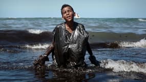 Un jeune garçon sort de l'eau souillé de pétrole sur la plage d'Itapuama, à Cabo de Santo Agostinho, au Brésil, le 21 octobre 2019. 

