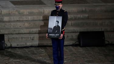 Un garde républicain porte le portrait de l'enseignant assassiné Samuel Paty lors de l'hommage national à la Sorbonne le 21 octobre 2020.